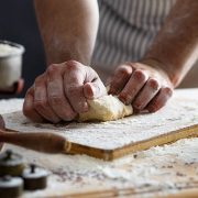 Close up of male baker hands kneading the dough with flour powder.